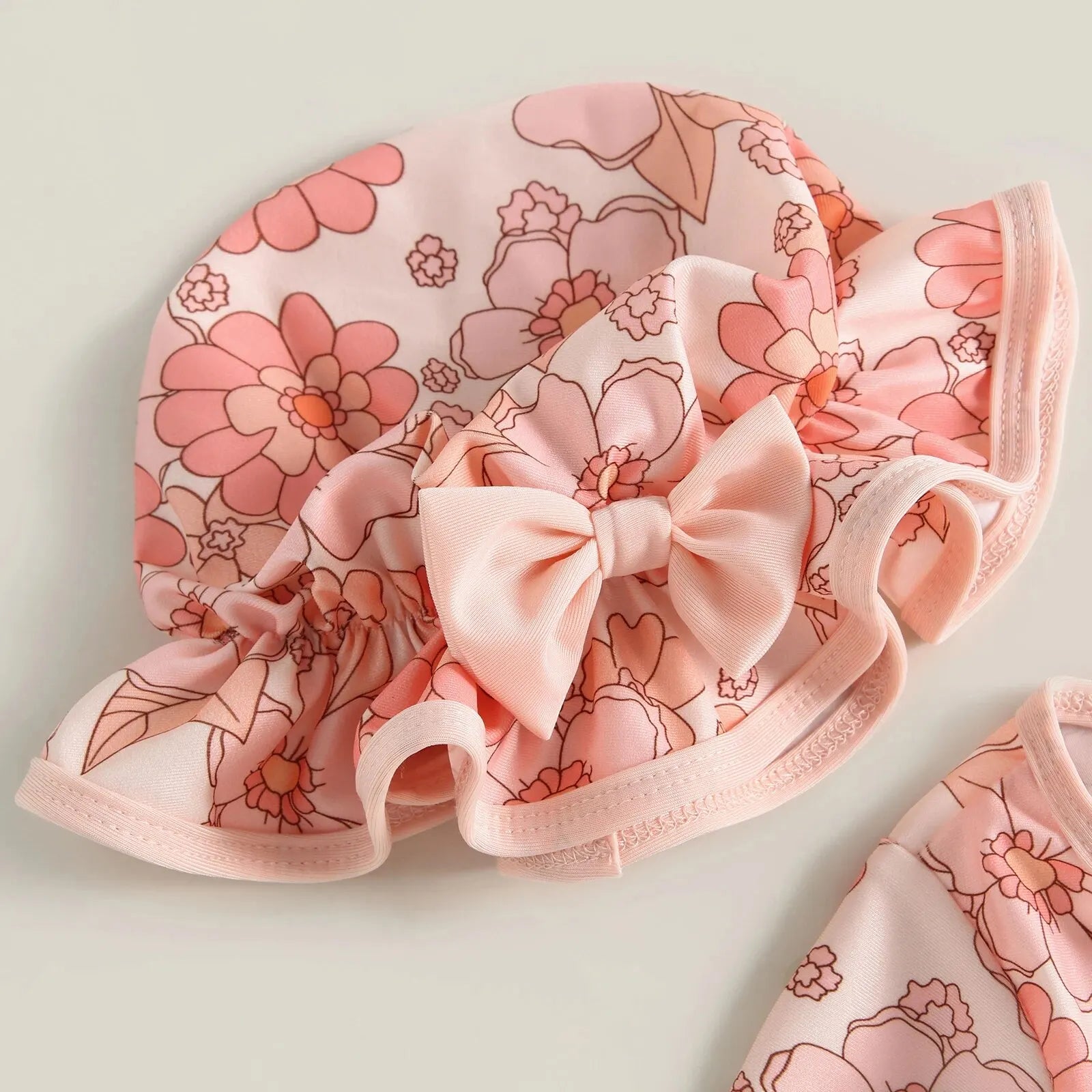 Baby girl wearing a floral flamingo print one-piece swimsuit by Baby Bubble, featuring bright colors and playful tropical design.