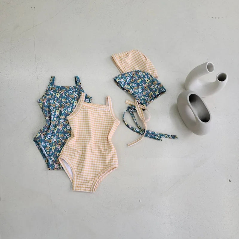 Baby girl in Baby Bubble one-piece swimwear set with sun hat, featuring colorful patterns and sun protection in a pool setting.
