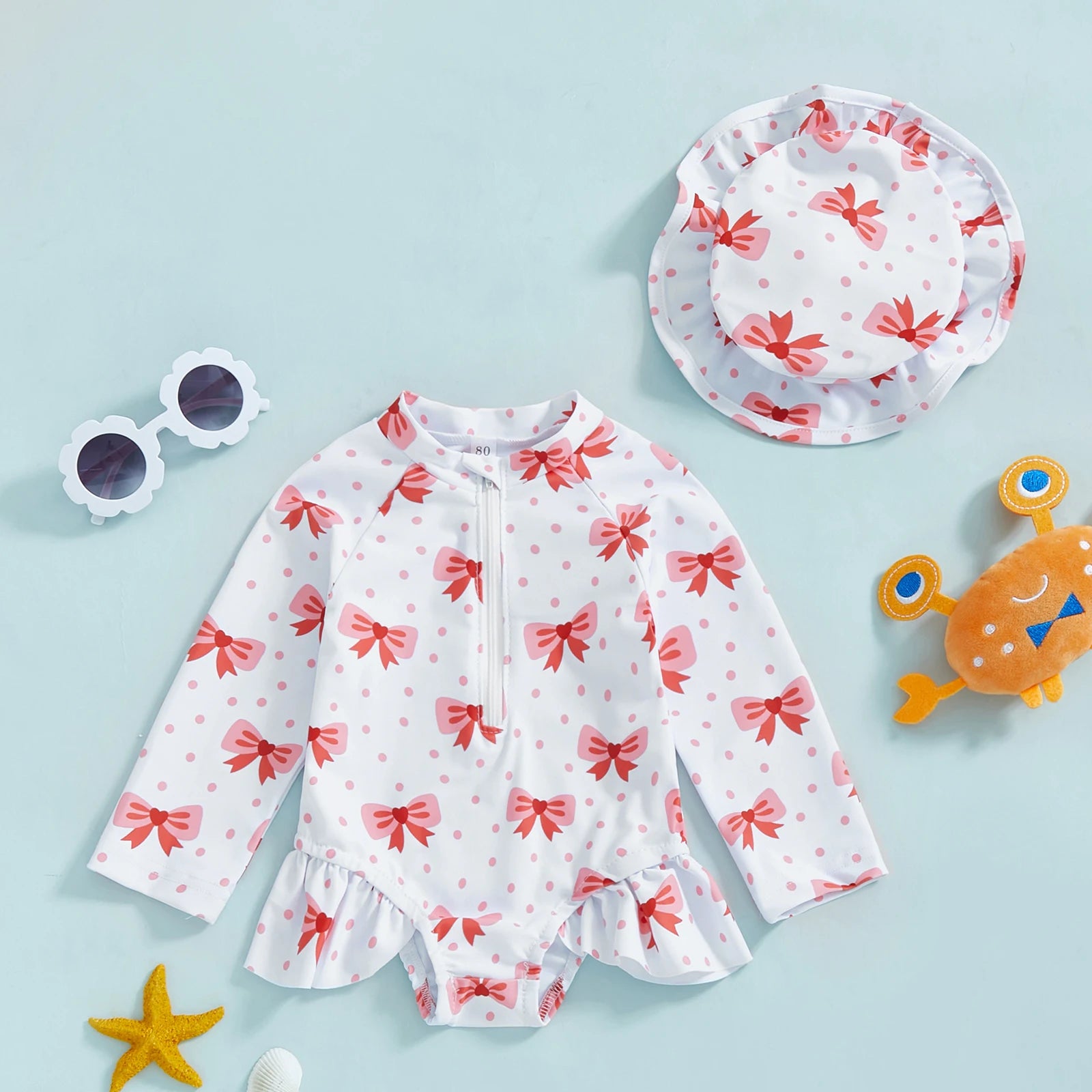 Baby girl wearing Baby Bubble floral rash guard with hat, zip-up swimwear featuring colorful flower pattern and sun protection.