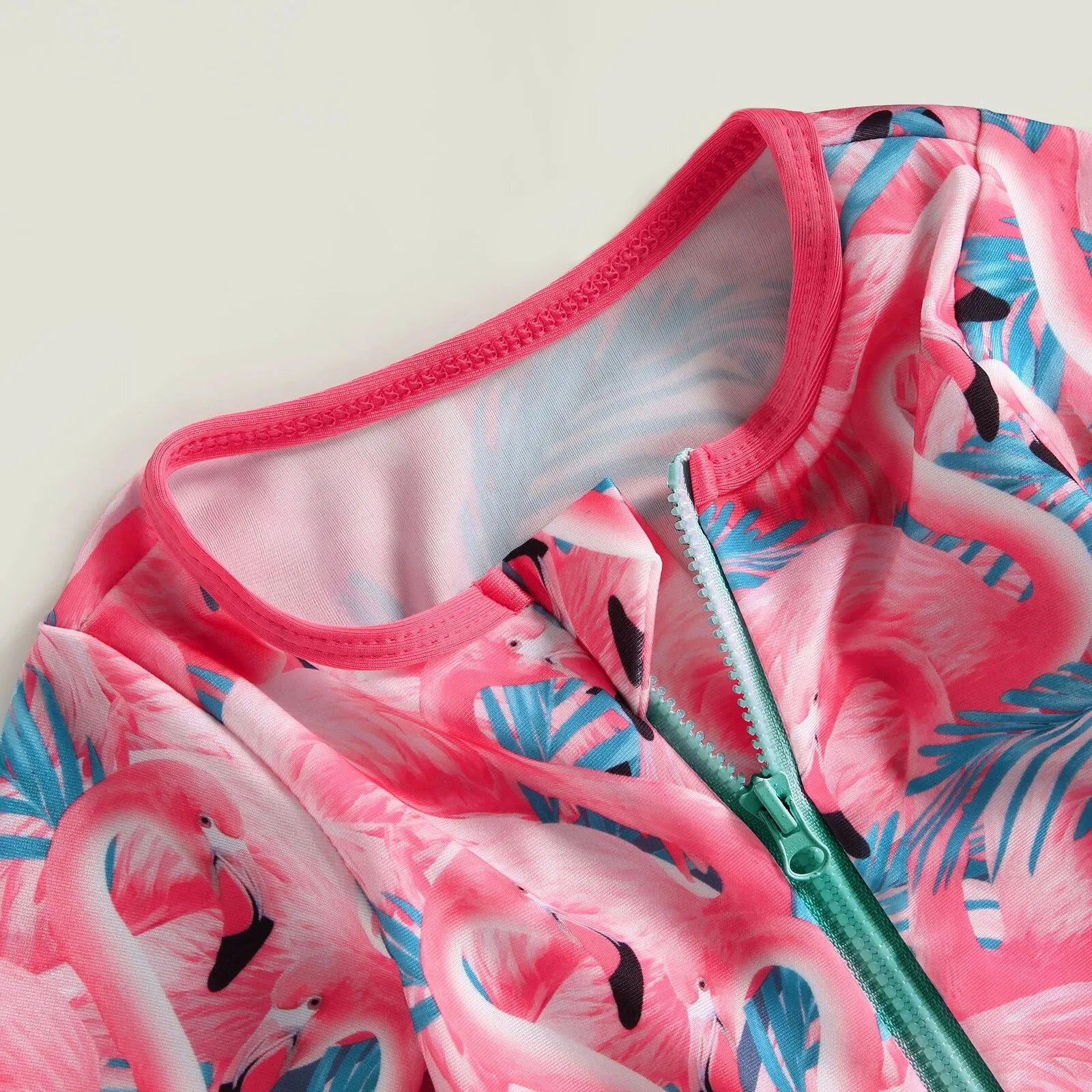 Baby girl wearing a floral flamingo print one-piece swimsuit by Baby Bubble, featuring colorful tropical design and ruffled straps.