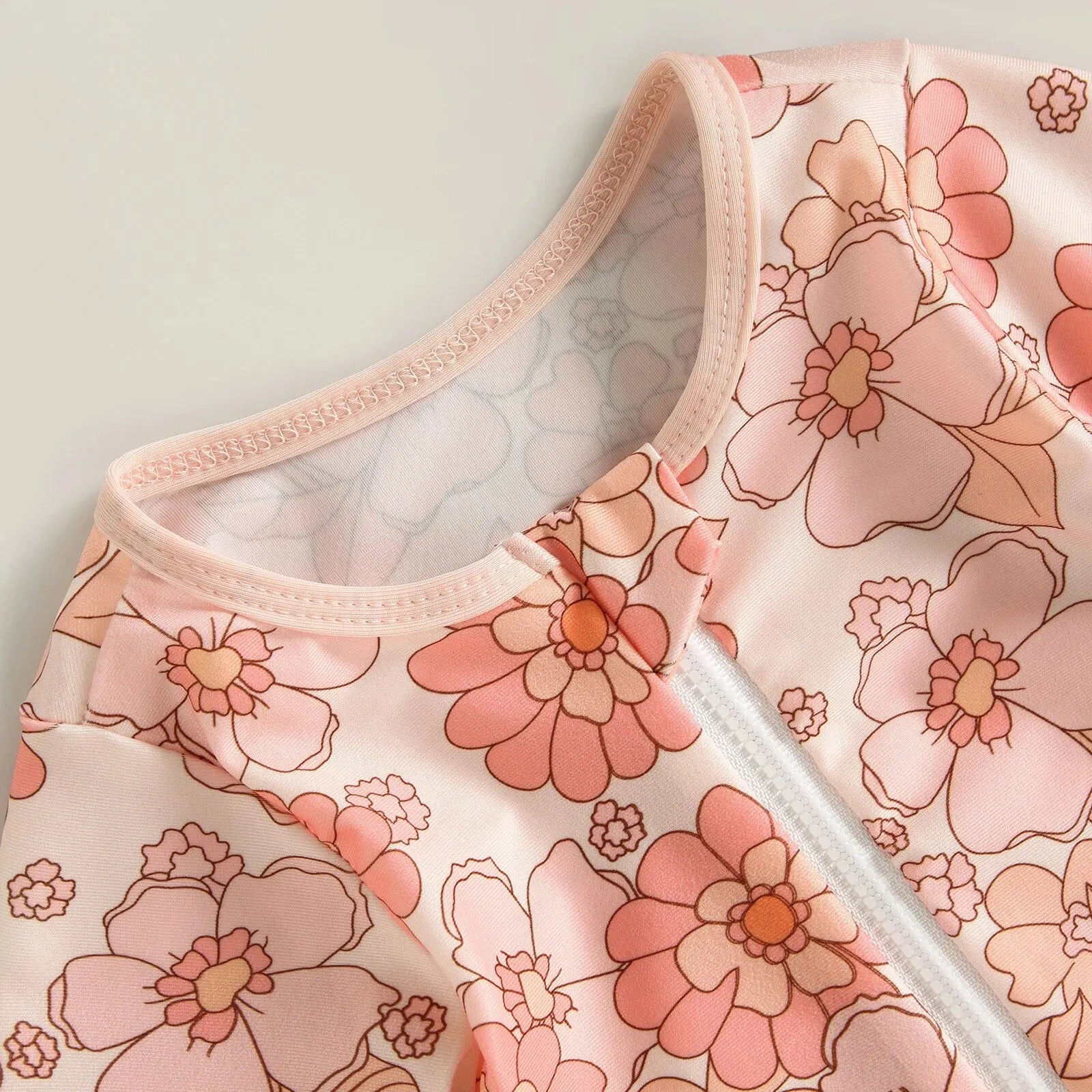 Baby girl one-piece swimsuit by Baby Bubble with a floral flamingo print, featuring colorful flowers and flamingos on lightweight swimwear.
